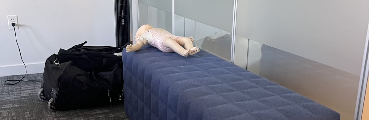 photo of a bench seat in a conference room and on the far end is a baby cpr dummy