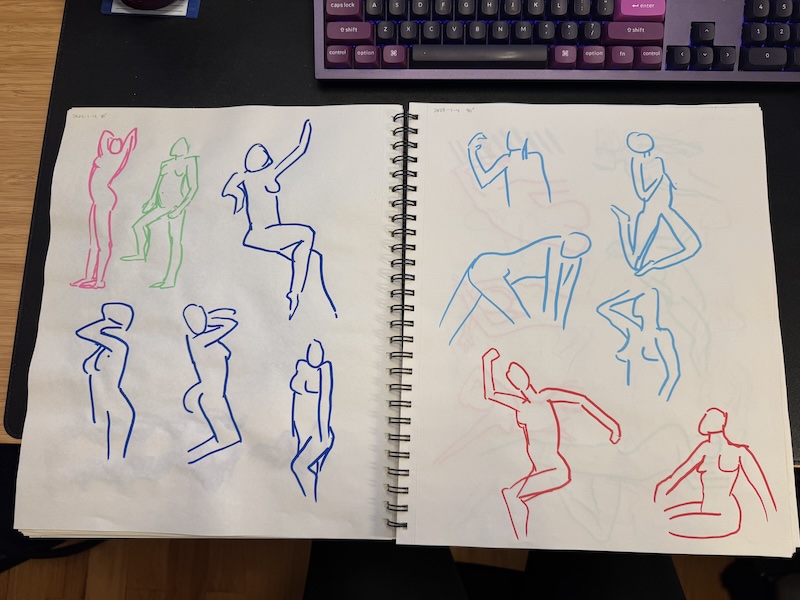 photo of my large sketchbook open to two pages of paint marker nude figure sketches done in 30 seconds. on the left page i have pink, lime, and cobalt blue figures. on the right page, light blue and red