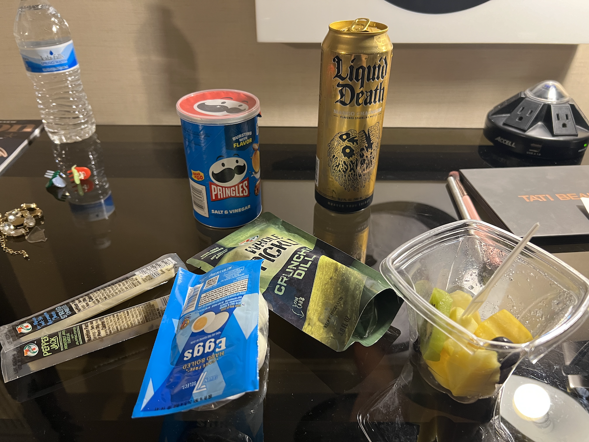 photo of a hotel desk and i've got pringles, seltzer, cheese sticks, hard boiled egges, pickles and fruit, all from 7-eleven