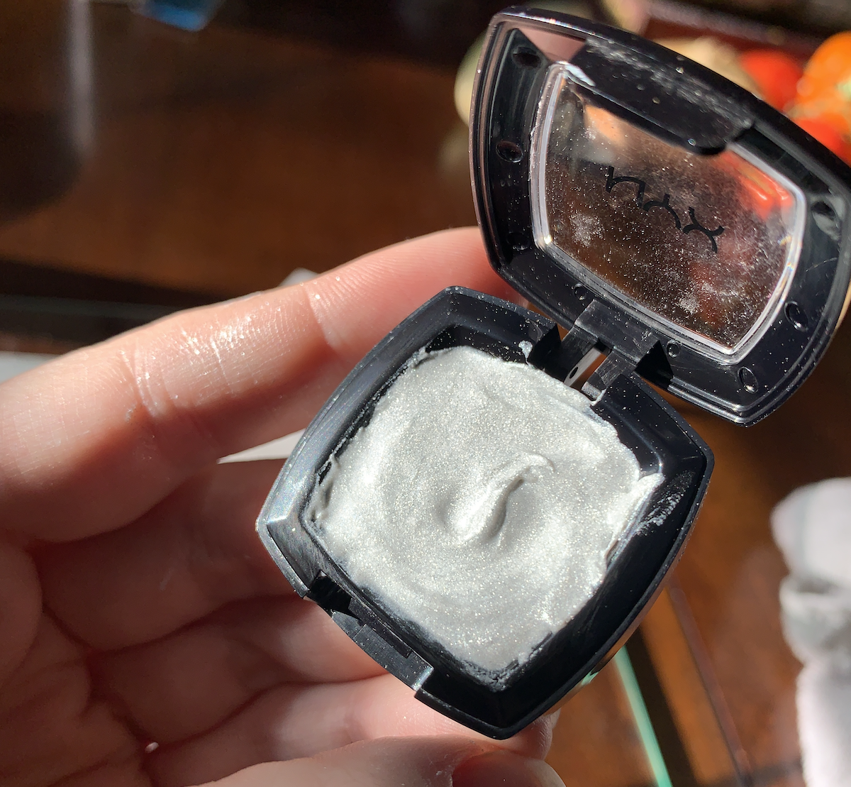 photo of me holding up my eyeshadow pan that's filled with the watercolor i made of it