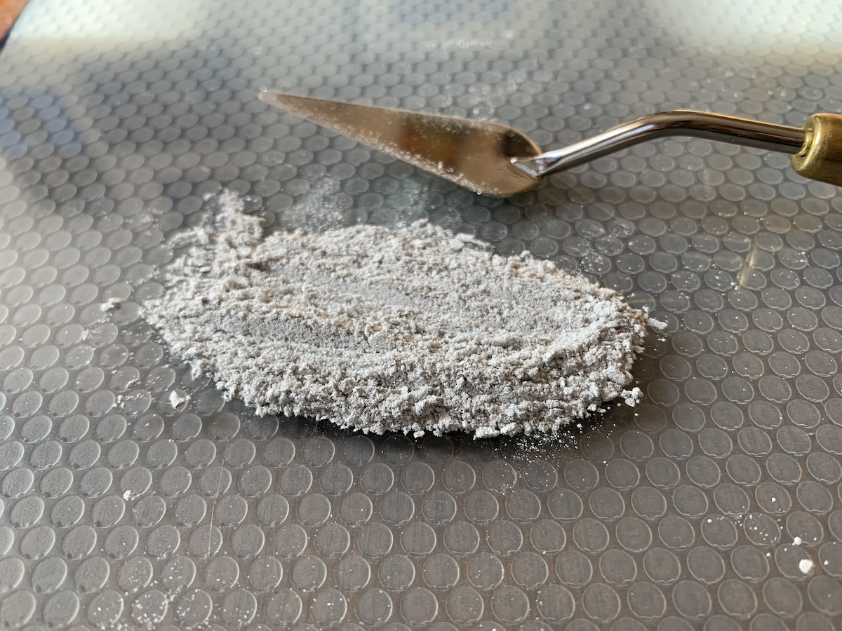 photo of the eyeshadow in powder form in a pile on my glass slab next to the palette knife