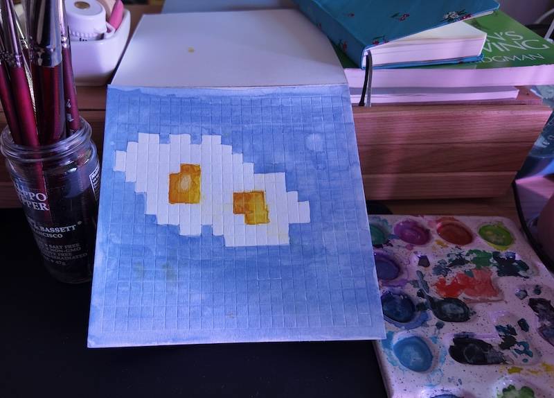 photo of pixel watercolor sketchbook on page 1, a couple of pixel art fried eggs
