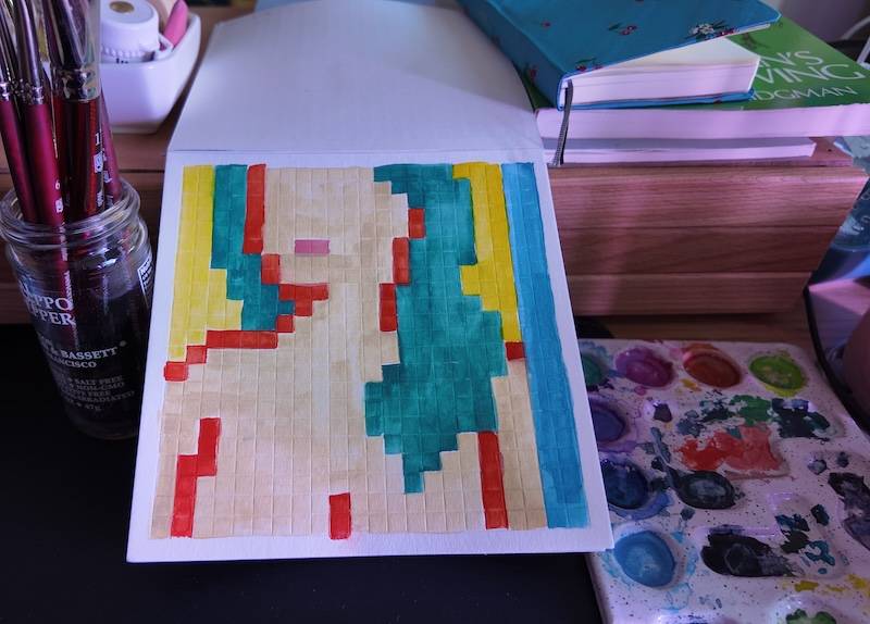 photo of pixel watercolor sketchbook on page 3, a pixel portrait of a woman with red outline and green hair