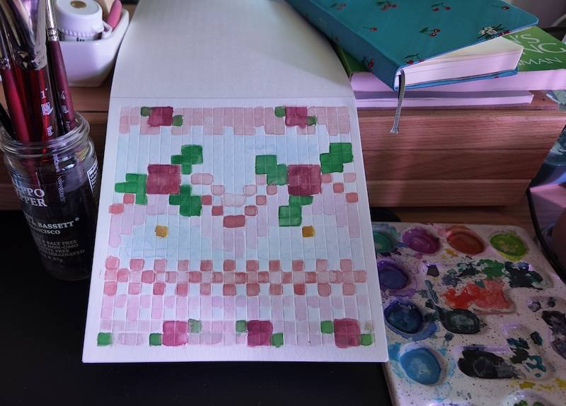 photo of pixel watercolor sketchbook on page 17, a pixel pattern inspired by a pink floral vintage cake