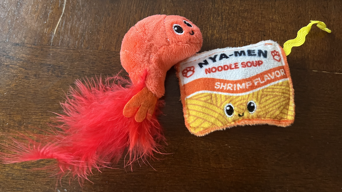 photo of 2 cat toys, one is a shrimp with a feather and the other is a fake packet of ramen