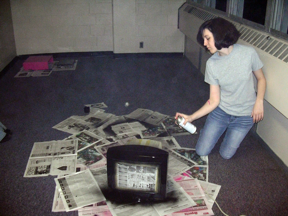 photo of me in a dorm common room with newspaper all over the floor and on it i've got a computer tower i spray painted pink and i'm there spray painting a crt monitor black
