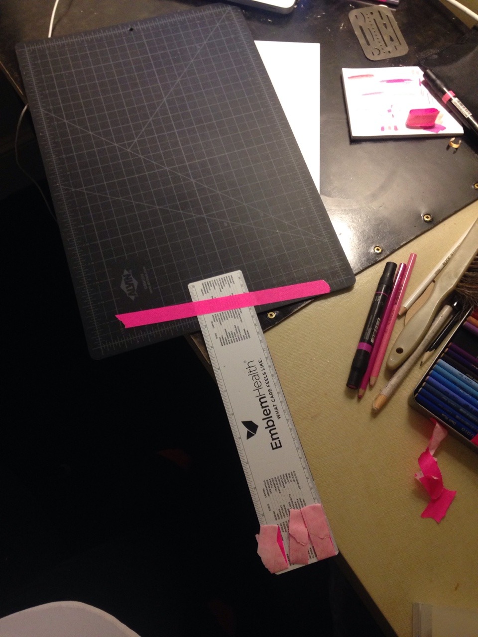 photo of a ruler and mat taped together with hot pink artist tape and some pieces of tape on one end which i was hoping would grab my paper so i can pull it up