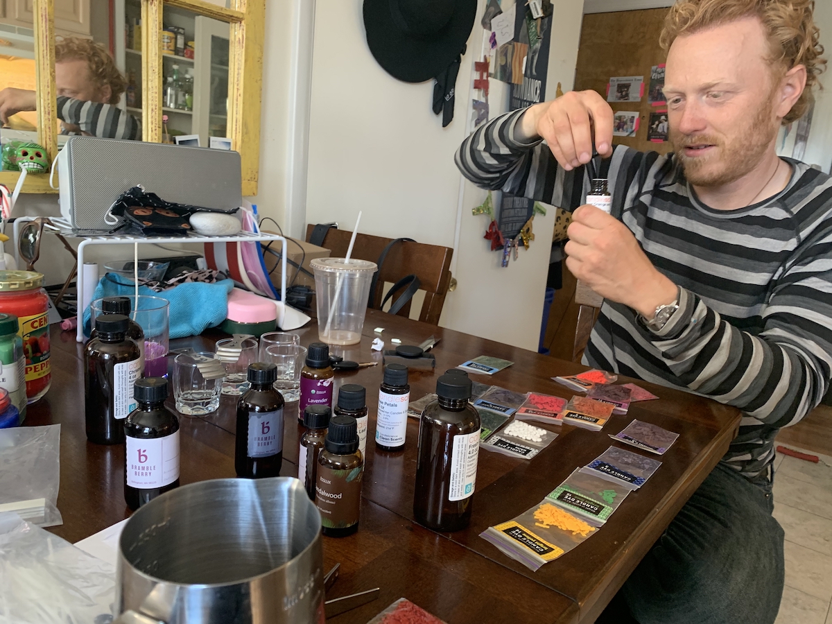 photograph of my friend tyler looking at different bottles of fragrance oils on my kitchen table