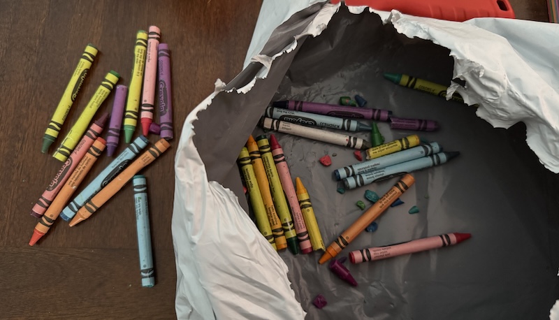 photo of my torn open polymailer full of broken crayons and some crayons on the table